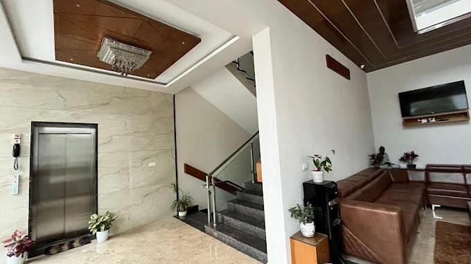 Reception area featuring with a staircase, a brown sofa, and wooden accents.- Sukhi - A Luxury Stay Inn, Chikkamagaluru