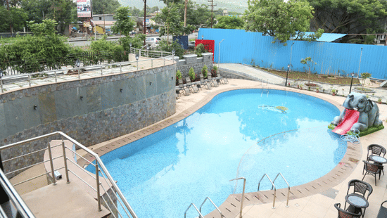 An image of a swimming pool and beside it there are seating area - VITS Lonavala.