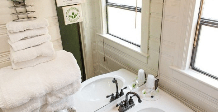 Overview of a Vanity area at Shaver Lake Village Hotel with white towels, toiletries, and a framed window in the background.