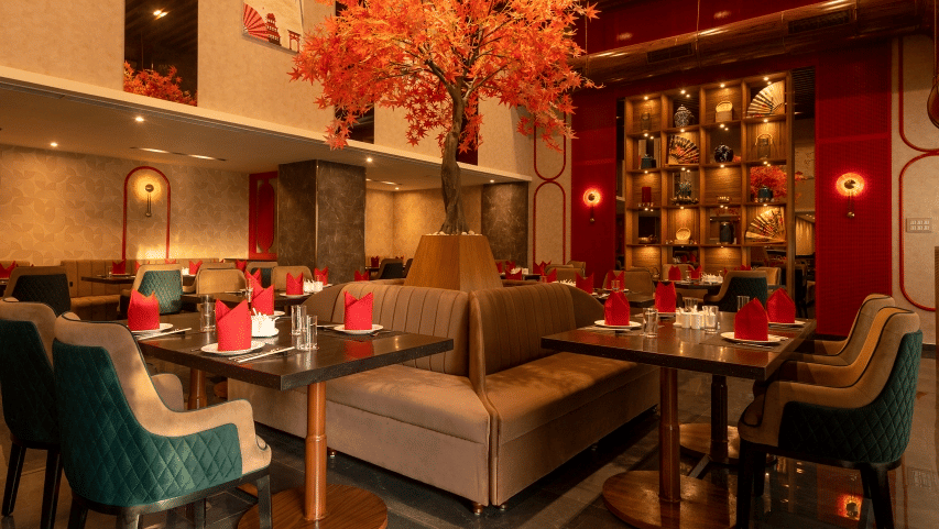 A restaurant interior with booth seating and a decorative tree, at Goldfinch Hotels & Resorts.