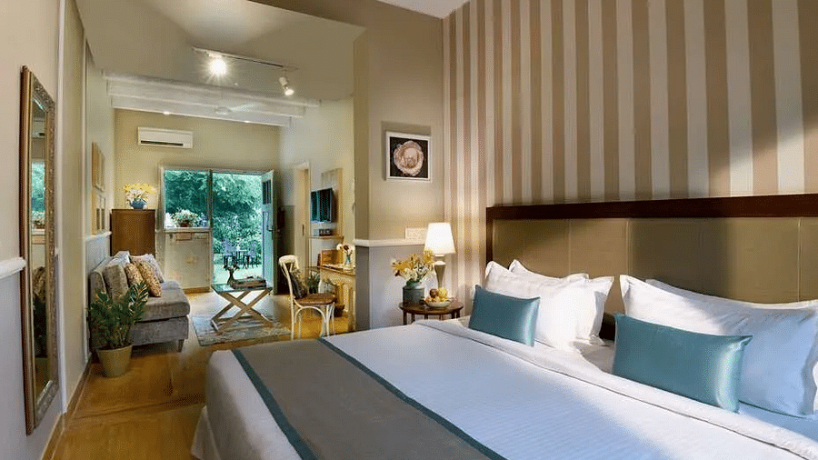Room interior at Karma Chalets with a bed, blue cushions, bedside tables, lamp, mirror, and artwork on the wall.