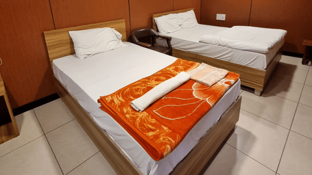Well-lit interior of Standard 3 Bed Room with cosy bedding and modern wooden interiors at Dream Vision Guest House, Diu.