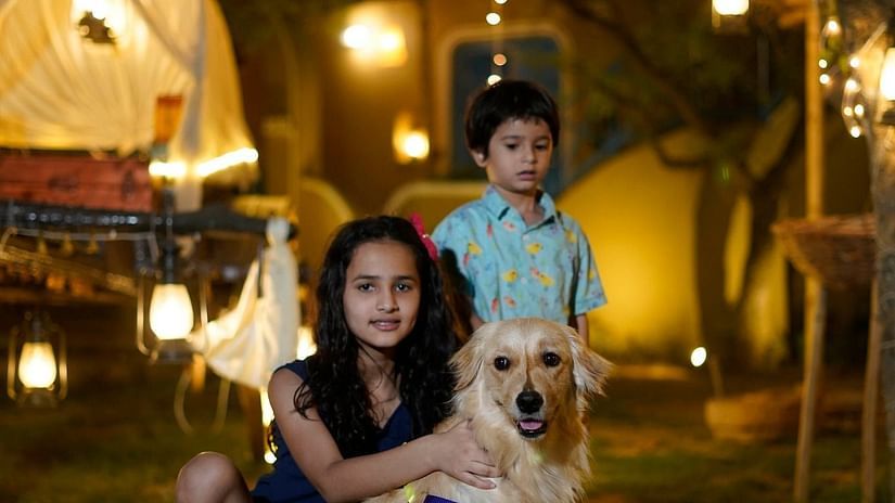 a woman and child sitting beside a dog at Themis Mudhouse - A Nature's Retreat Resort & Wellness