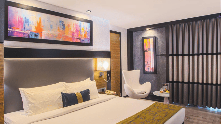 Elegant hotel bedroom showcasing a large double bed, wooden flooring, and modern wall art.