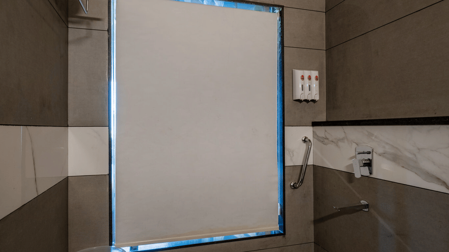 A well-lit bathroom area with tiled walls, a white privacy screen on a window.