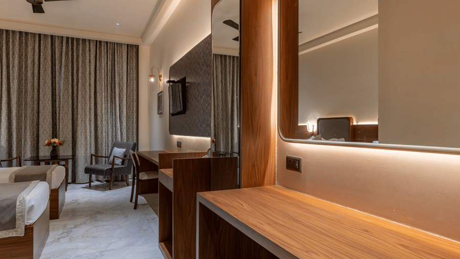 Hallway view at Hotel Highway Prince, Behror, showing a long wooden desk with a built-in mirror and a view into an adjoining bedroom.