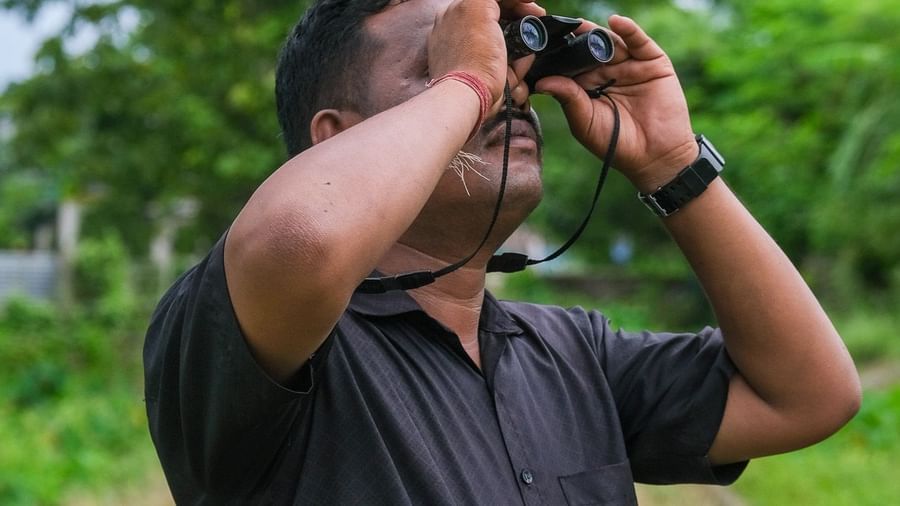 A man birdwatching at Rhino and River BluSalzz Collection, Pobitora.