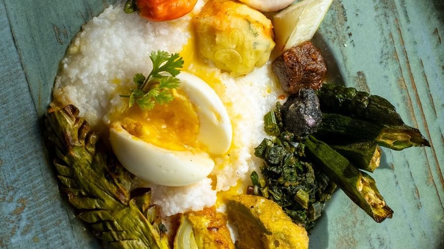 Authentic Assamese thali featuring rice, egg, fried vegetables, and chutneys served on a ceramic plate at Rhino and River BluSalzz Collection, Pobitora.
