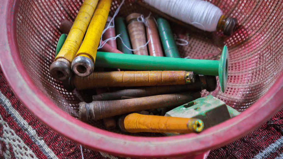 A top-down perspective showing an open basket filled with vibrant, colourful threads and wooden tools .