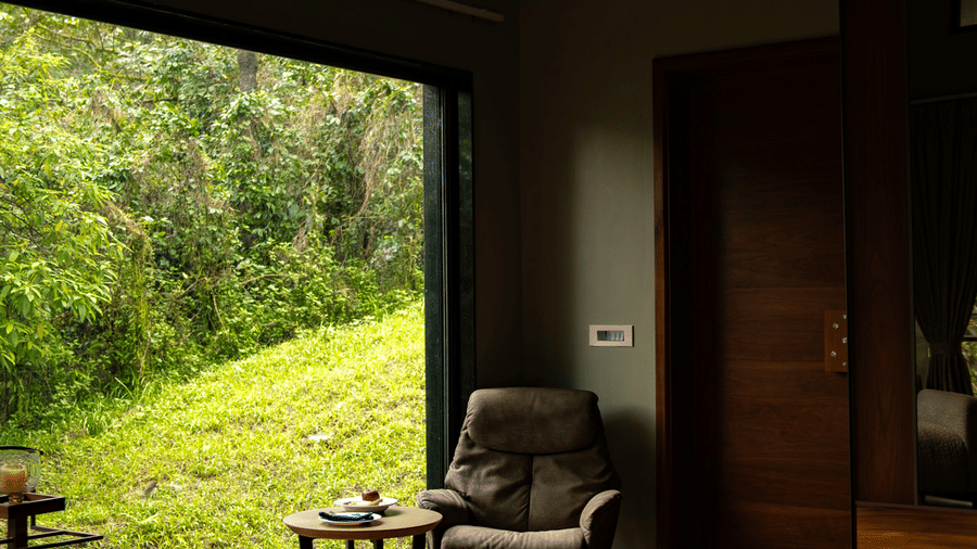 A comfortable armchair and a small table sit near a large window overlooking a lush green field at Stanley Revelation.