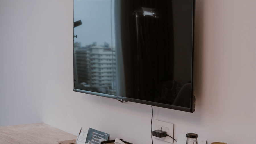 A room features a wall mounted television, a long wooden counter, and a grey tray holding snacks at Tiara by MPS.