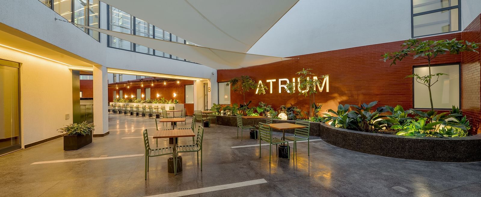 A modern outdoor seating area with a large, red 'ATRIUM' sign on the wall.  - The Pelican Hotel, Accra