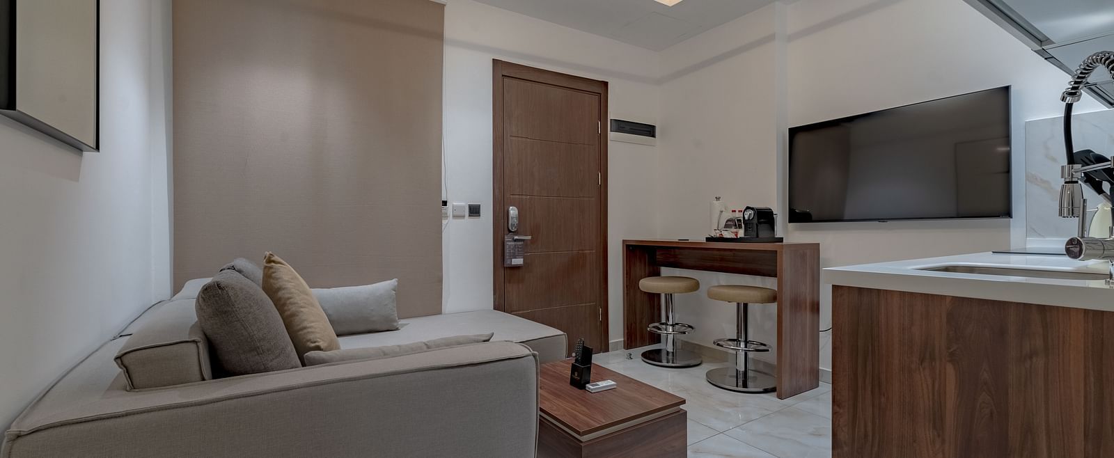 Modern, well-equipped kitchen in a Deluxe Room with wooden cabinetry and stainless steel appliances. - The Pelican Hotel, Accra