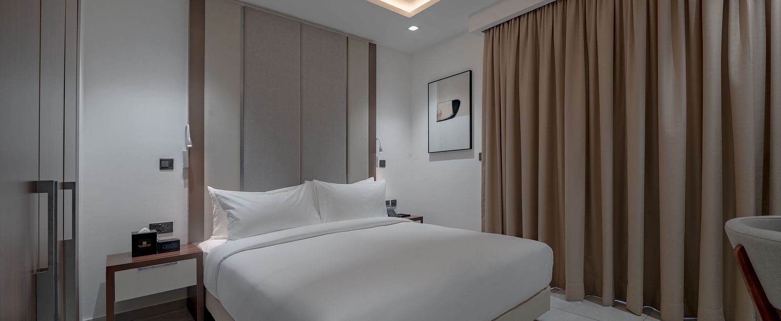 A well-lit Standard Room with a king size bed next to curtains. - The Pelican Hotel, Accra