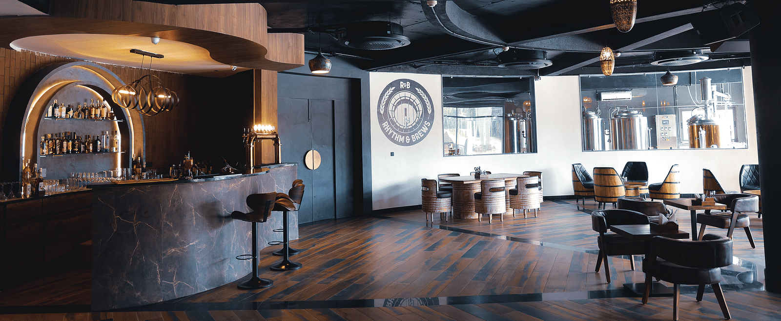 A bar with a unique ceiling design and patrons seated at tables at The Qualia Resort Club & Brewery, Udaipur.