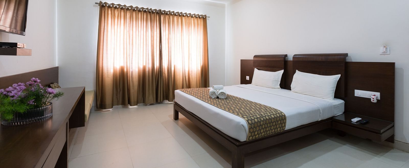 A bedroom with a bed, wooden furniture, and neutral-toned decor under soft lighting - Sanctum Suites BEL Road, Bangalore