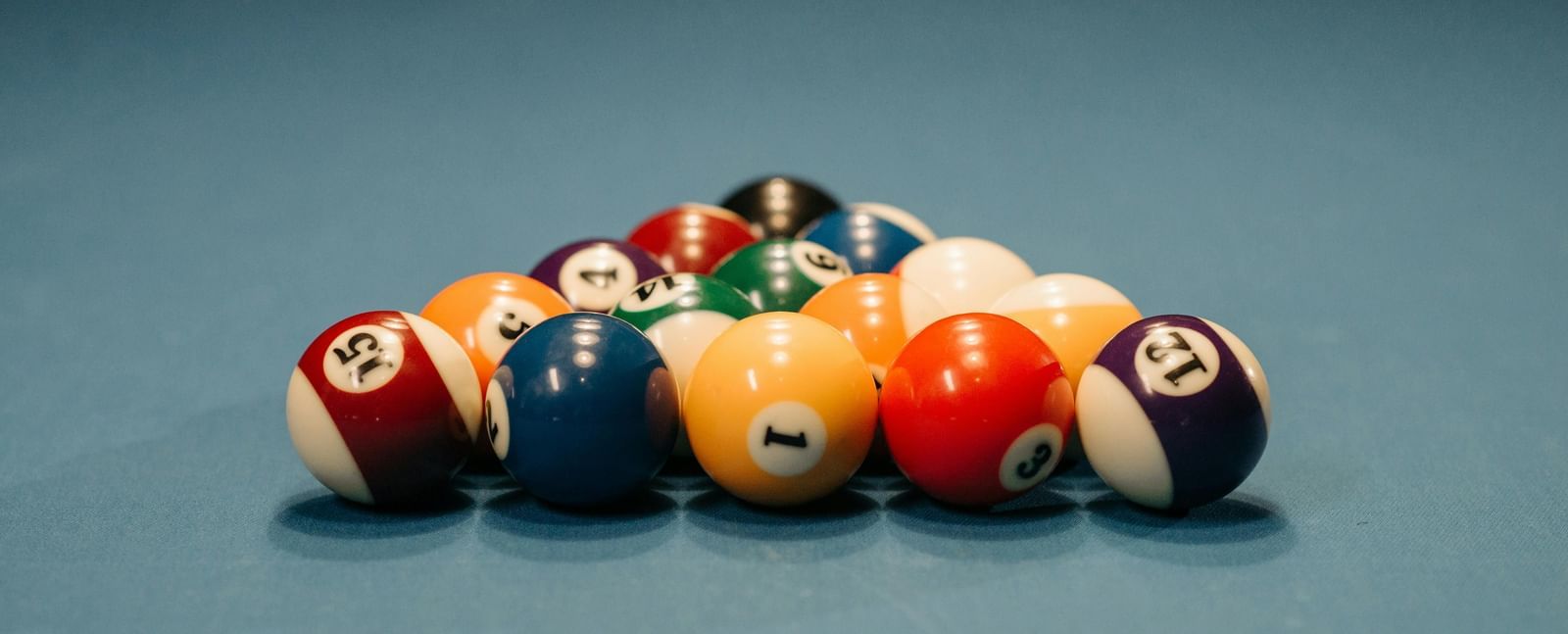 Pool balls arranged in a triangular rack on a blue pool table.