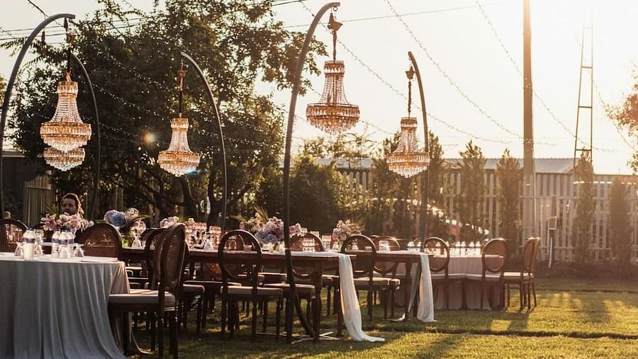 A banquet arrangement in an open garden with over head chandeliers. 