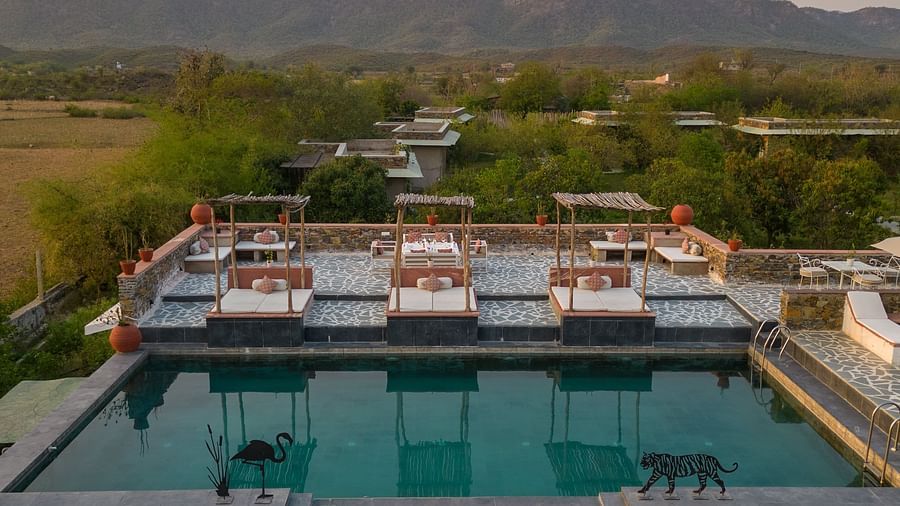 An image of a seating arrangement near the swimming pool in the open with the backdrop of sunset - Utsav Camp Sariska