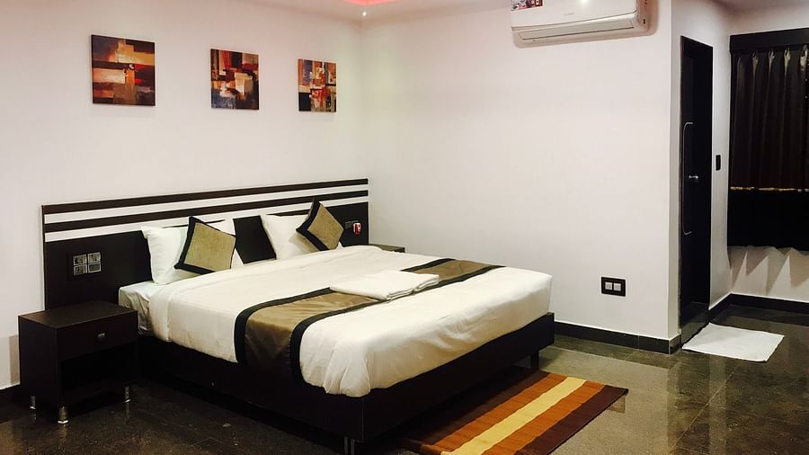 A room with a bed, a ceiling fan, and an air-conditioner at Parampara Residency, Kushalnagar.