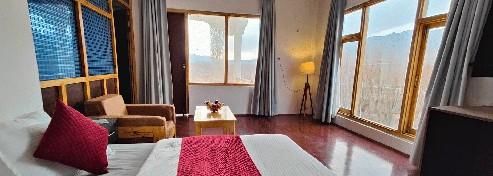 A bright, airy suite with a red bed runner and large windows overlooking the grounds at Indus Serenity Retreat.