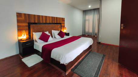 A wide-angle view of a bedroom featuring warm ambient lighting from bedside lamps at Indus Serenity Retreat.