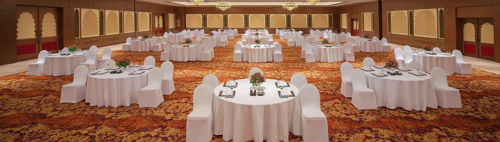 A banquet hall in Mahabalipuram with chandeliers, carpeted floors, and a cluster-type seating arrangement – Kaldan Samudra Palace, a Beautiful Wedding Venue ECR