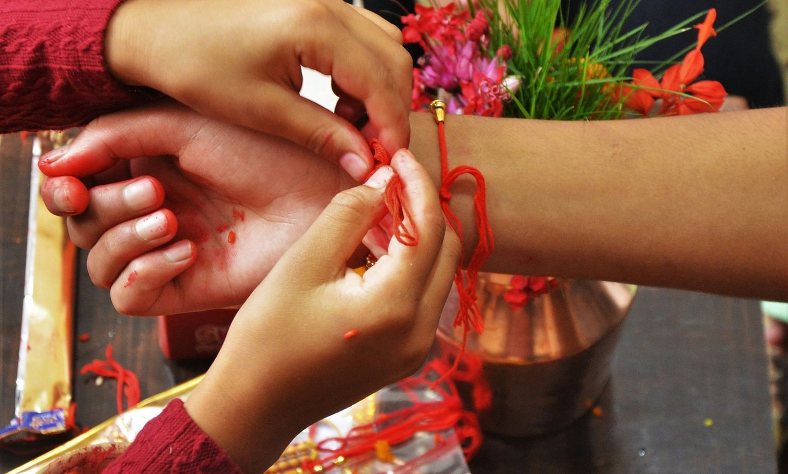 A close up shot of two hands where one is tying a thread on another wrist