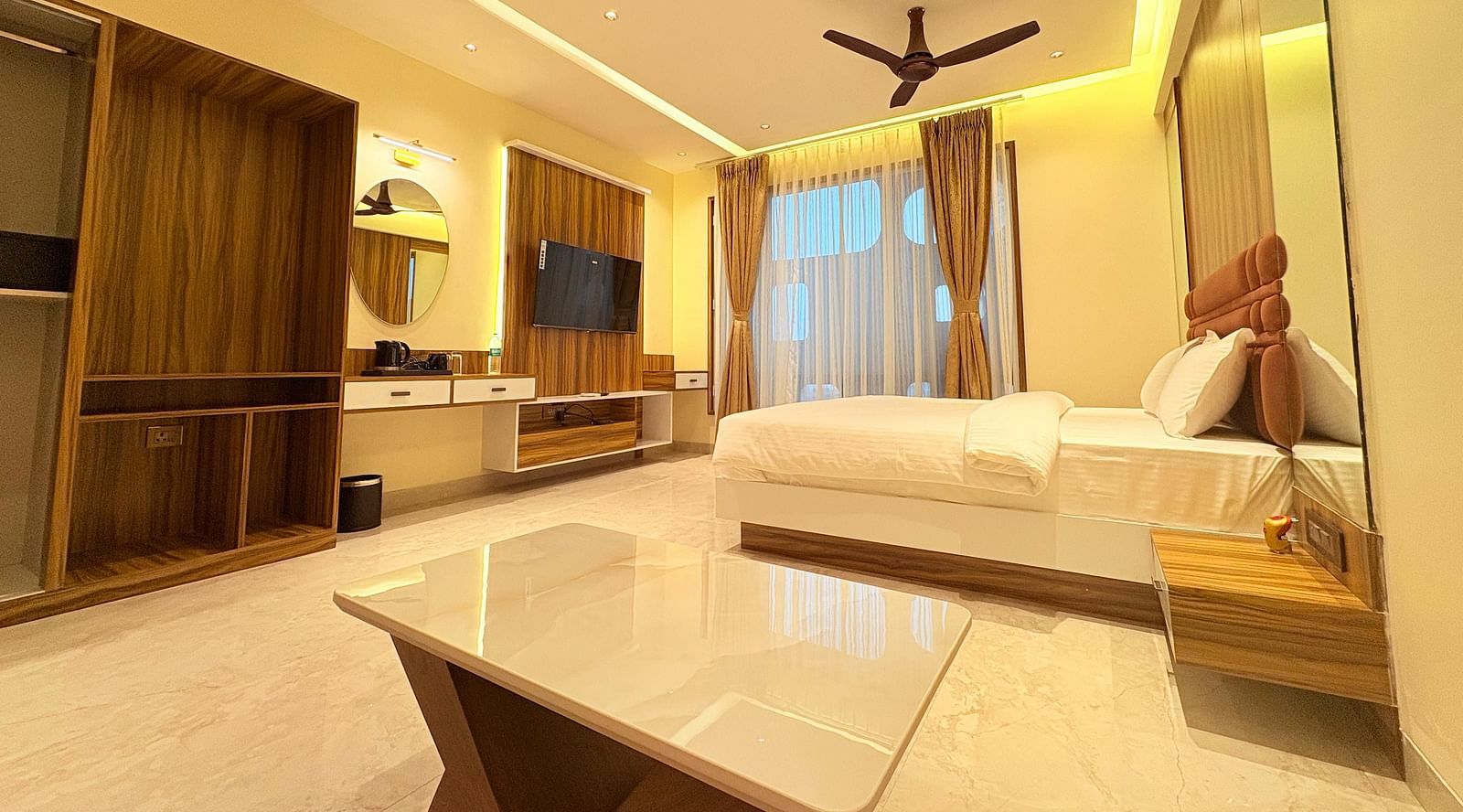 Side view of the bedroom featuring a wall-mounted television, a king size bed, and a window covered by curtains at Hotel Mumbai House, Vashi.