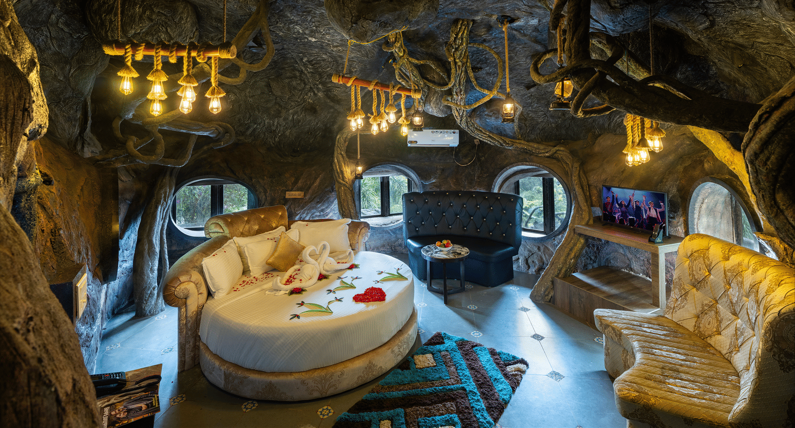The bedroom in Cave Room at Parakkat Nature Hotel and Resorts, Munnar, featuring a circular bed, vanity mirrors, and ceiling accents mimicking a stone cave interior.