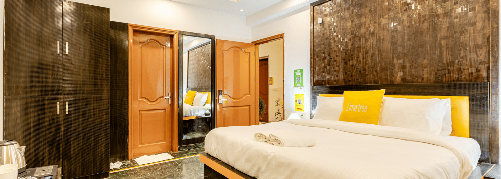 side view of the king size bed and a peek in the washroom in the superior king room at Lime Tree Hotels and Banquet Hall Near Huda Metro, Gurgaon