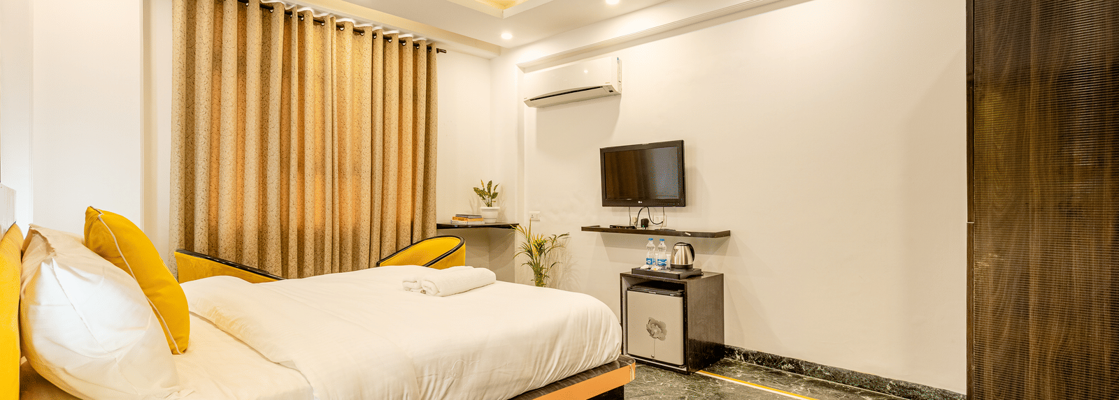 side view of the king size bed and a television in front of it in the superior king room at Lime Tree Hotels and Banquet Hall Near Huda Metro, Gurgaon