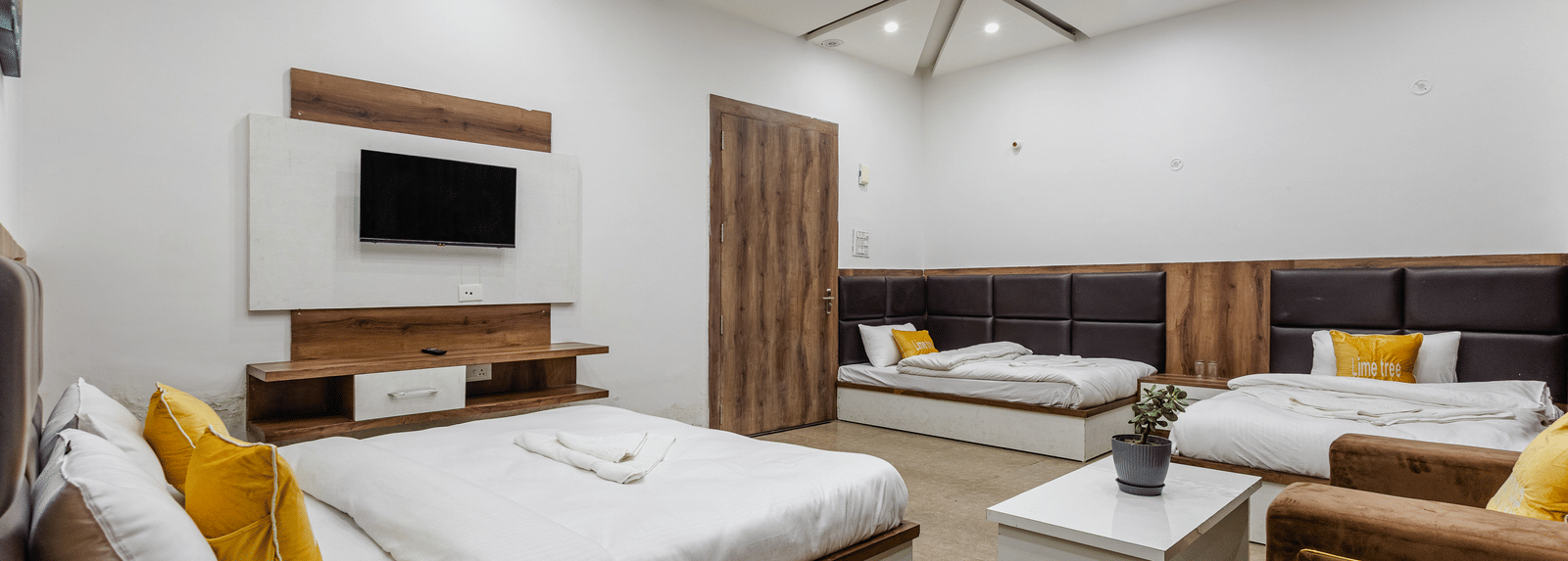 A bedroom featuring wooden furniture, ceiling fan, and a TV unit - Lime Tree Hotels & Banquet, Vrindavan