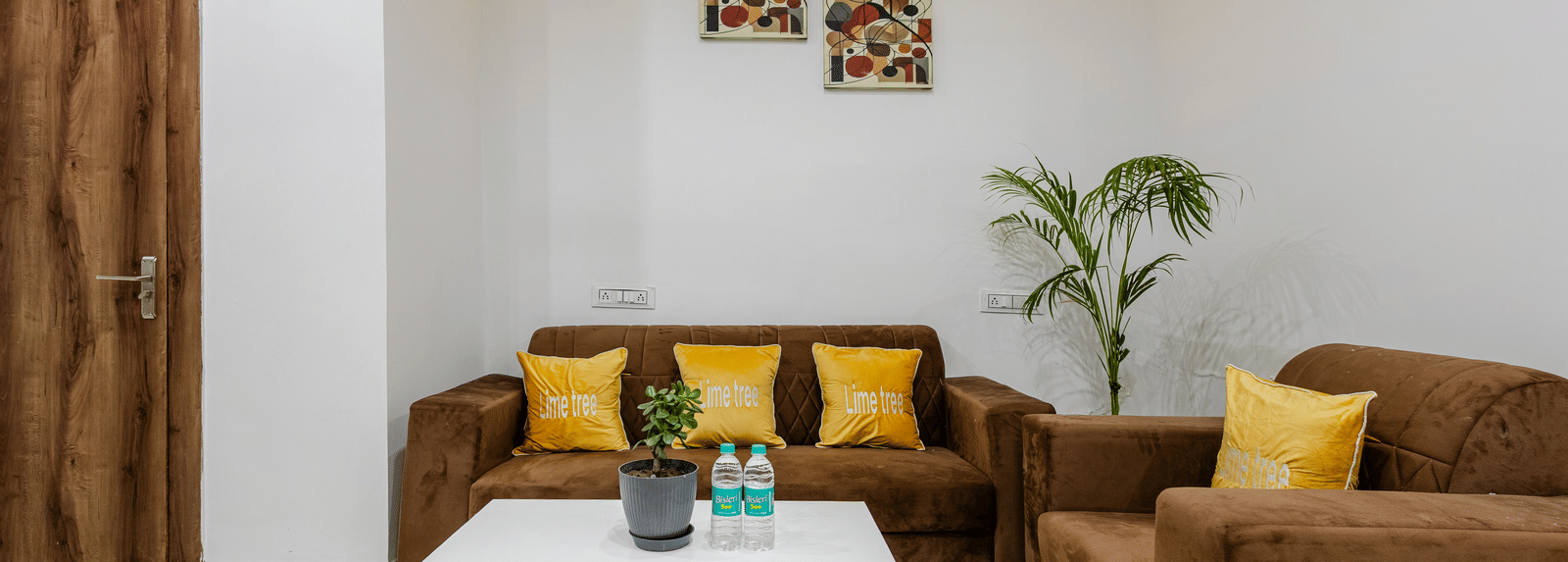 A four seating brown coloured couch with yellow coloured cushions at Lime Tree Hotels and Banquet, Vrindavan.