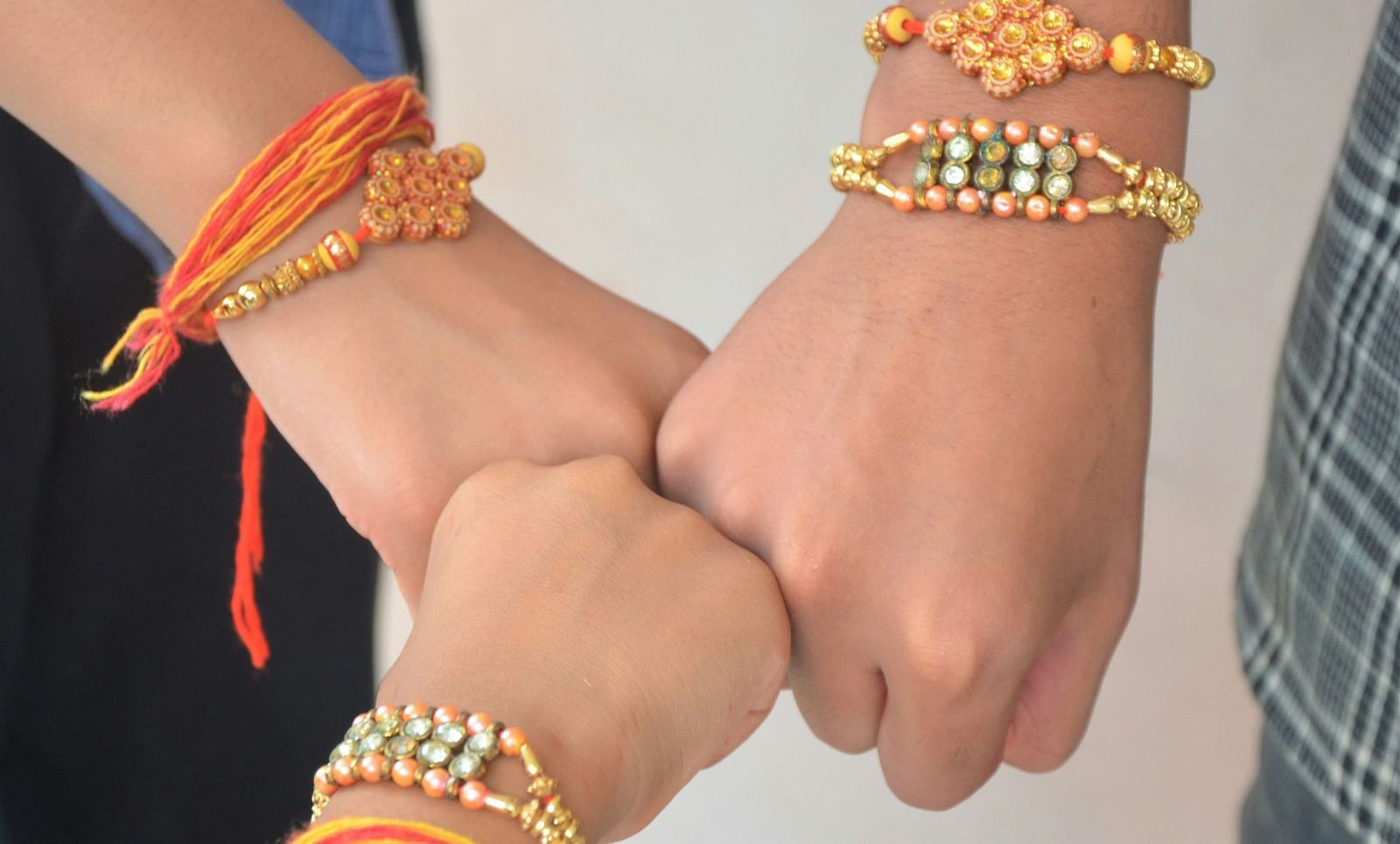 A close up shot of three hands with Rakhi tied on their wrists