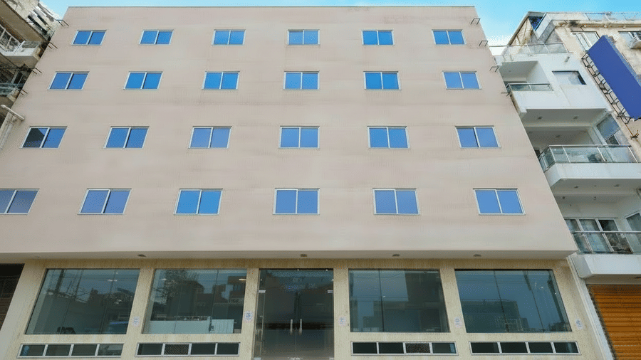 Facade of Hotel Corporate Suites standing under a bright blue sky, showcasing many uniform windows