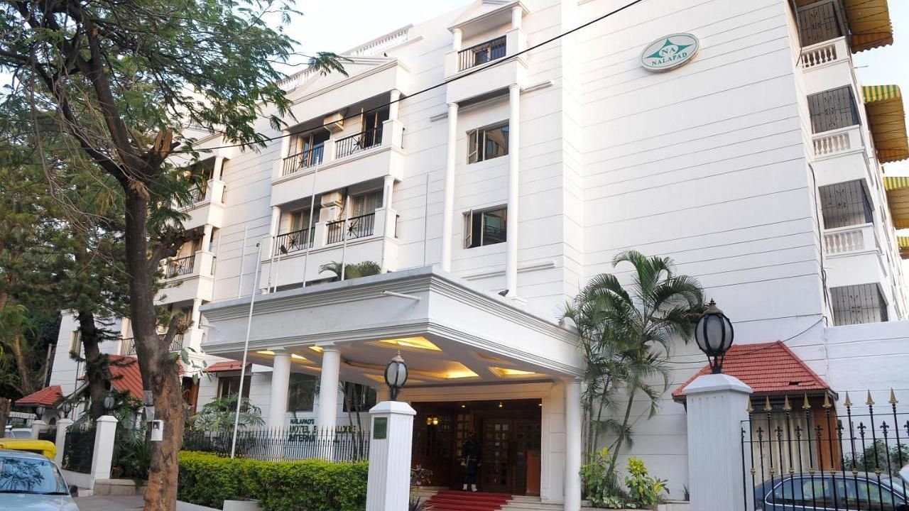 Nalapad Hotel Bangalore International, a white building with a covered entrance, landscaping, and parking.