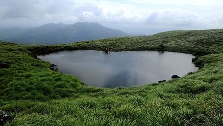 A scenic hilltop lake with misty mountains in the background.