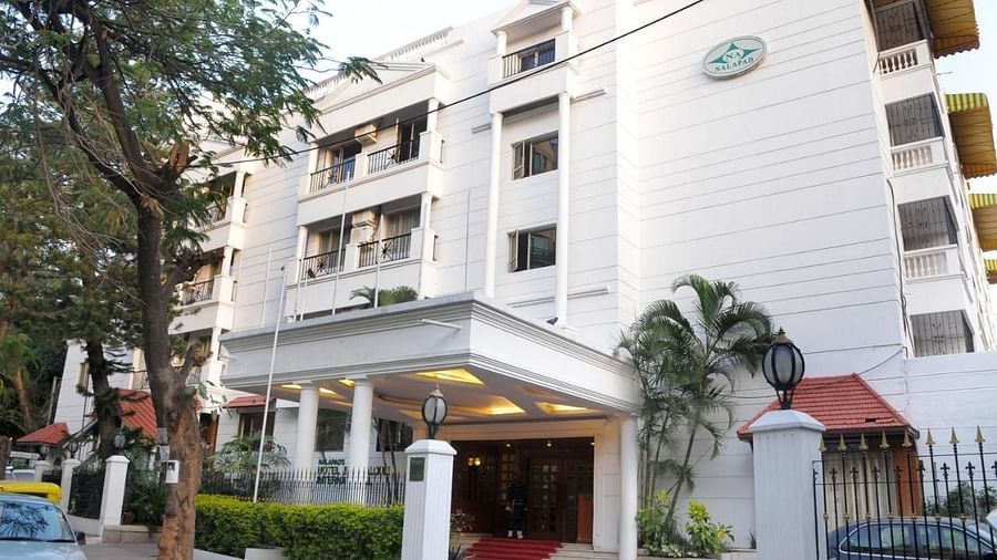 Nalapad Hotel Bangalore International, a white building with a covered entrance, landscaping, and parking.