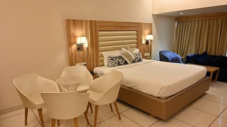 Comfortable hotel room at Rang Lords Inn, with a bed, seating area, and elegant wooden headboard