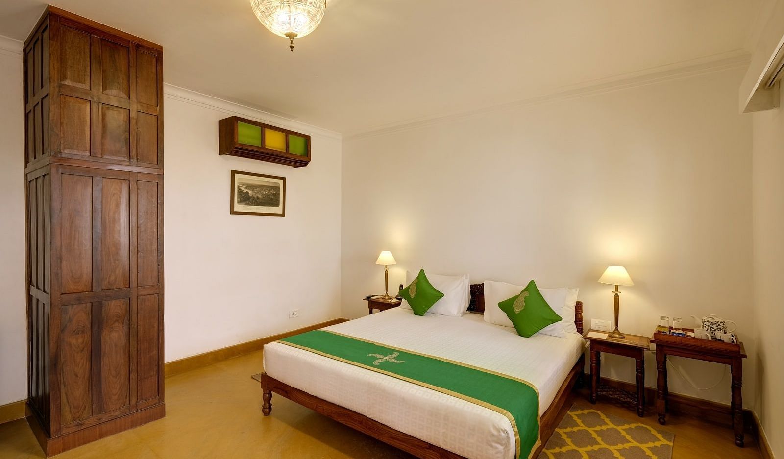 a comfortable bed decked with green cushions at Saraca Lucknow