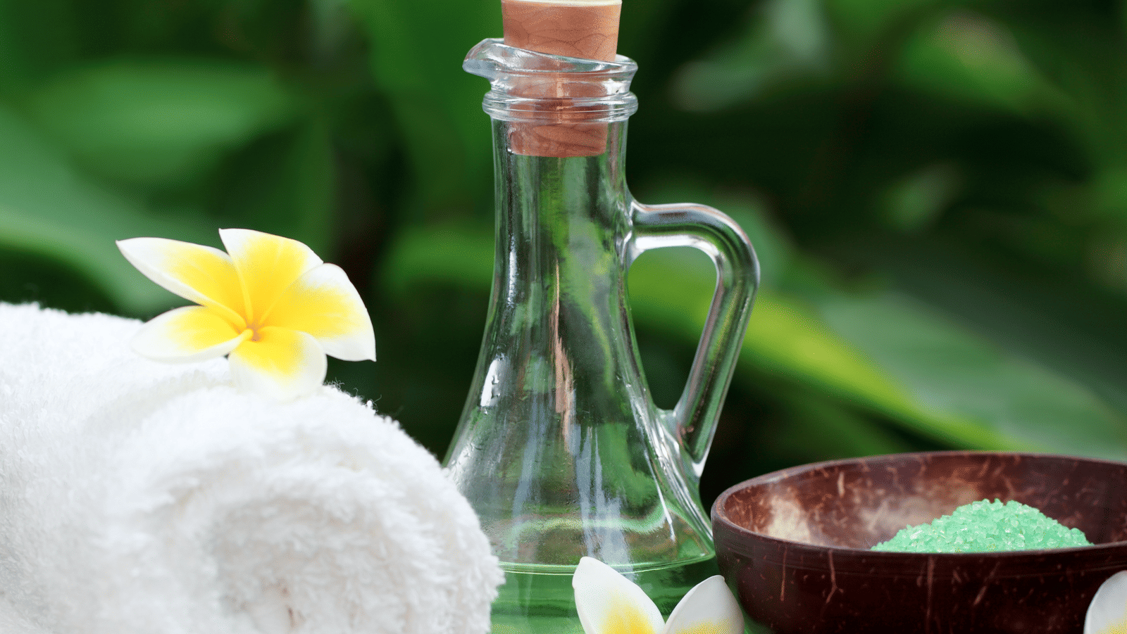  A serene spa setting featuring a rolled white towel, a bottle of oil, and a coconut shell bowl of green salts at Rhythm Lonavala