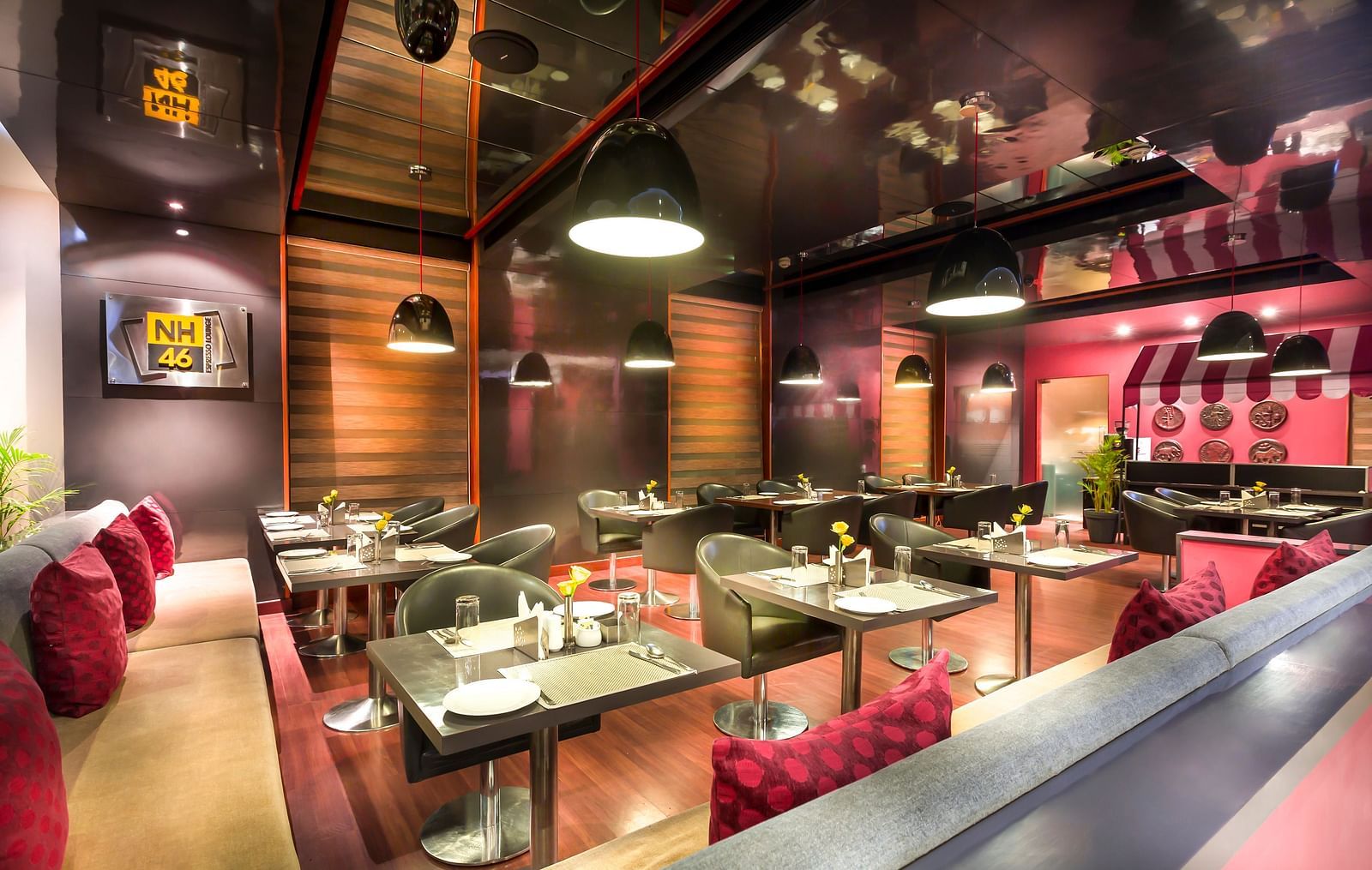 Modern restaurant interior with red accents, plush seating, and a reflective ceiling.