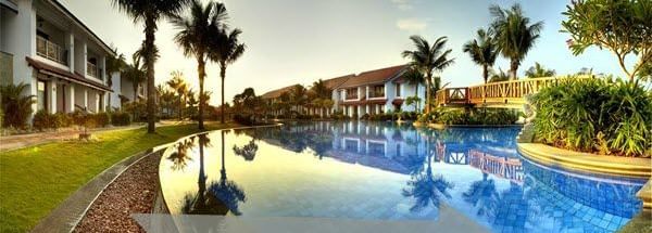 A swimming pool surrounded by buildings and palm trees with the text “Hotel Booking” visible in the image.