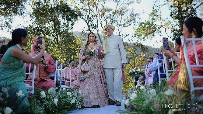 The bride and groom walking on the aisle surrounded by guests at The Sylvan Retreat, Dehradun.