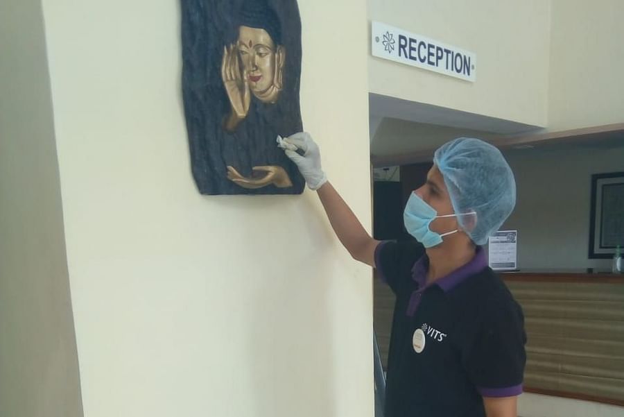 a staff member cleaning a picture at one of the hotels - VITS Hotels & Resorts
