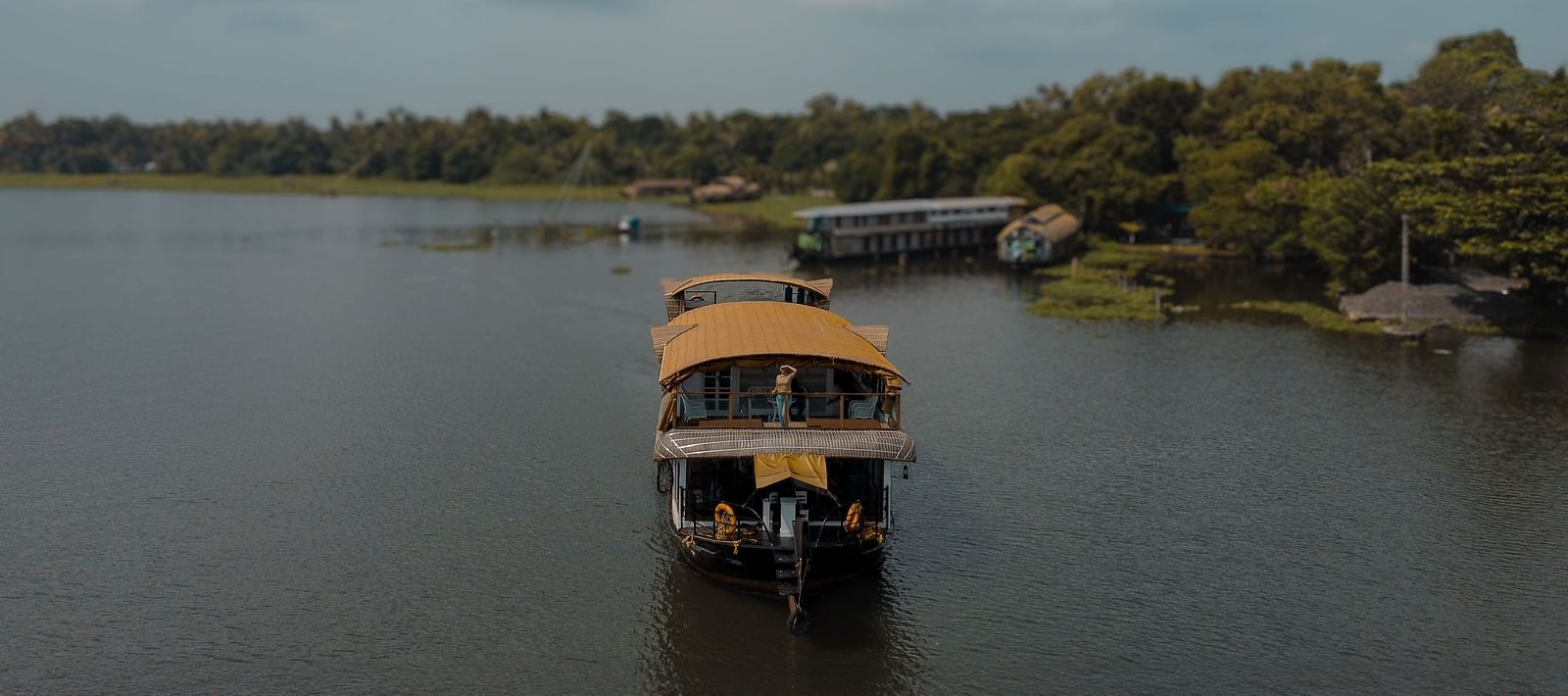 A cruise sailing across the Vembanad Lake with lush greenery in the background - BluSalzz Villas - Muhamma Resort, Alleppey