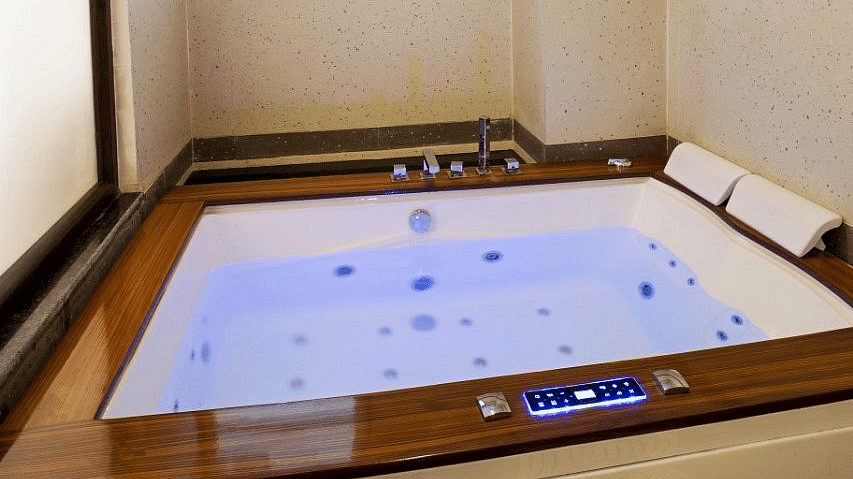 A Jacuzzi tub with blue lighting in the bathroom of the Suite at Regenta Inn DLS.