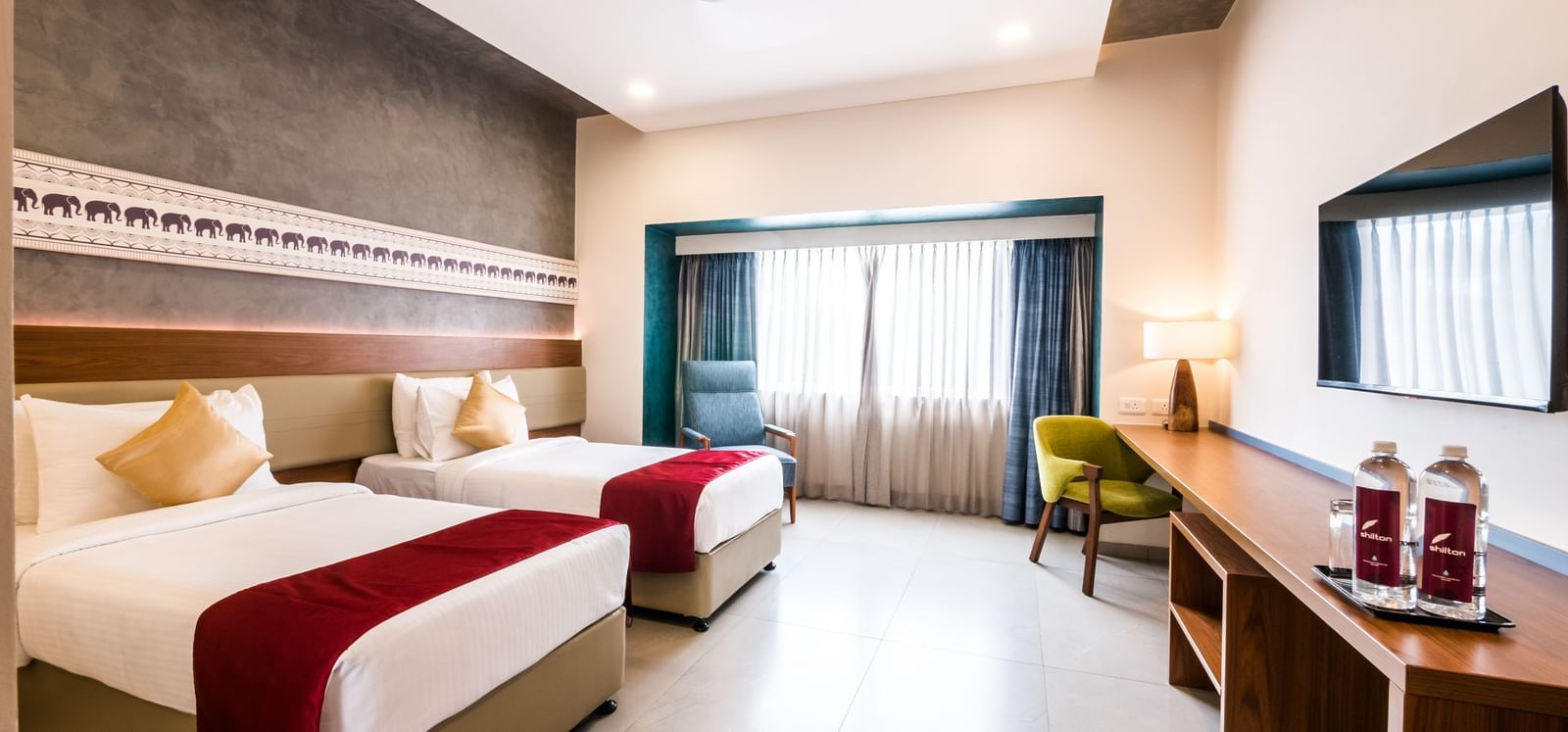 A spacious hotel room with a large bed and a comfortable seating area, offering a relaxing stay at Shilton Dee Cee.