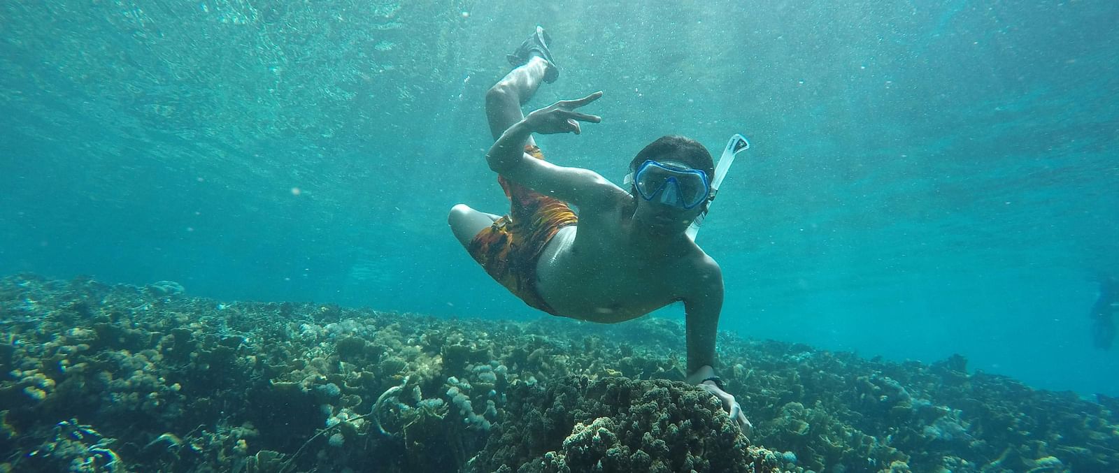 A person posing for a picture while holding a coral stone under water